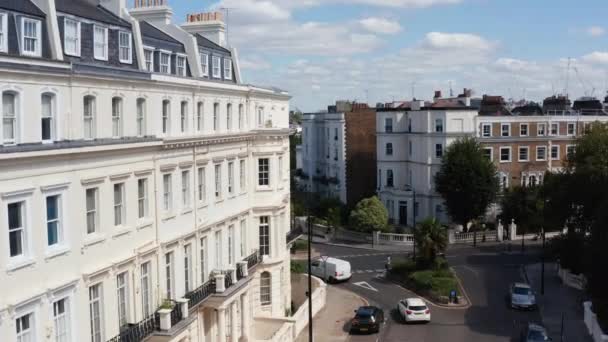 Vista aérea de coches que conducen a través de la intersección de la calle. Inclinado volar sobre la esquina de un gran edificio blanco en el barrio urbano. Londres, Reino Unido — Vídeo de stock