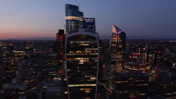 Fly around group of skyscrapers in modern business district. Evening aerial view of city. London, UK — Stock Video