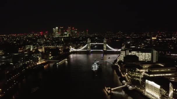 Вид с воздуха на Тауэрский мост через Темзу ночью. Знаменитая достопримечательность, освещенная ярким светом. Лондон, Великобритания — стоковое видео
