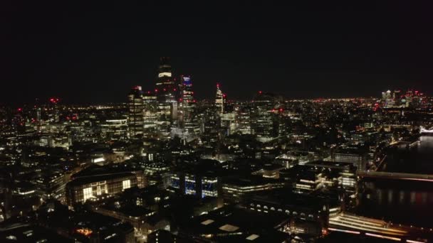 Nocna scena powietrzna. Tył ujawnia pejzaż miasta i mosty przez Tamizę. Światła miejskie nocą. Londyn, Wielka Brytania — Wideo stockowe