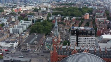 Saat kulesi olan eski tuğla binanın görüntüleri. Yukarıya doğru eğildiğinde gökdelenleri olan şehir manzarasını ortaya çıkar. Londra, İngiltere