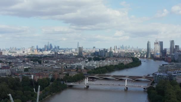 Creciente filmación sobre el río Támesis. Vista panorámica aérea de los edificios de la ciudad. Distrito residencial en la orilla del río y rascacielos en el centro de negocios en la distancia. Londres, Reino Unido — Vídeo de stock