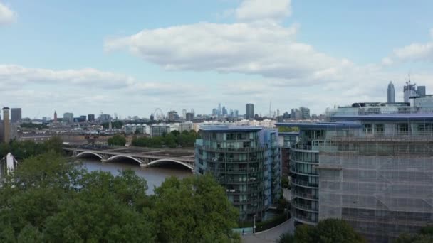 Riprese in aumento del paesaggio urbano. Moderni condomini a Tamigi riva del fiume e panorama della città rivelando dietro gli alberi. Treno rosso diretto alla stazione Victoria. Londra, Regno Unito — Video Stock