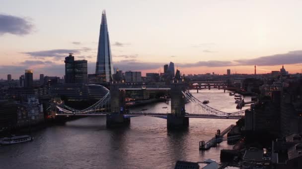 Snímek a pan záběry jednoho ze symbolů města. Slavný Tower Bridge přes řeku Temži proti růžové obloze po západu slunce. Vodní hladina odrážející soumračnou oblohu. Londýn, Velká Británie — Stock video