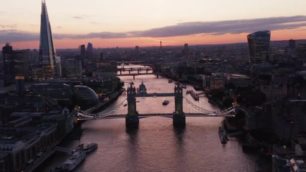 Hátrafelé repül a Temze felett. Csodálatos kilátás nyílik a Tower Bridge-re és számos más hídra a folyón keresztül. Rózsaszín szürkületi eget tükröző vízfelület. London, Egyesült Királyság — Stock videók