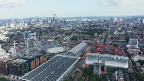 Slide and pan view of St Pancras train station. Воздушный панорамный вид на город с группой высотных современных небоскребов вдали. Лондон, Великобритания — стоковое видео