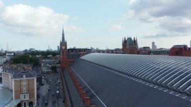 Camden ilçesindeki St. Pancras tren istasyonunun çatısında alçak uçuş. Saat kulesiyle tarihi tuğla binaya gidiyorum. Londra, İngiltere