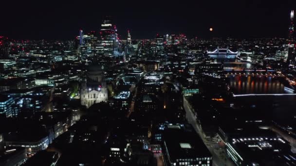 Achterwaartse kanteling onthult het nachtelijke stadsbeeld. Stadsverlichting van grote stad. Saint Pauls kathedraal, moderne wolkenkrabbers en bruggen over de rivier de Theems. Londen, Verenigd Koninkrijk — Stockvideo