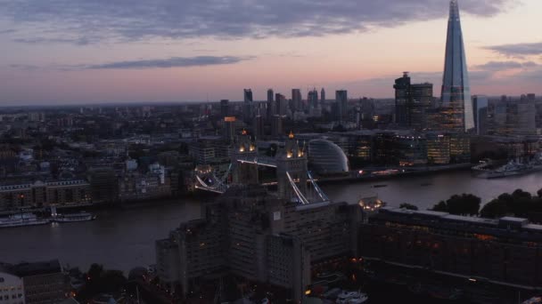 Slide e pan tiro de paisagem urbana da noite. Ponte da Torre Iluminada e arranha-céus na margem sul do rio Tâmisa. Londres, Reino Unido — Vídeo de Stock