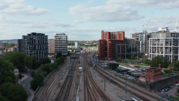 Şehirdeki modern konut binalarının etrafında giden tren raylarında ilerliyor. Londra, İngiltere — Stok video