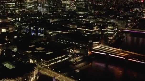 Vuela por encima del río Támesis por la noche. Vista aérea de edificios en el paseo marítimo alrededor de la estación de tren de Cannon Street. Inclinado hacia arriba revelan de rascacielos del centro. Londres, Reino Unido — Vídeos de Stock