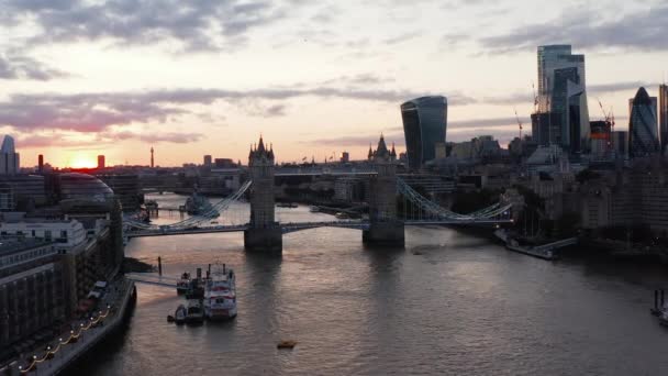 Slide και pan πλάνα του διάσημου ιστορικού Tower Bridge ενάντια στον ουρανό ηλιοβασίλεμα. Ψηλά μοντέρνα κτίρια στην όχθη του ποταμού Τάμεση. Λονδίνο, Ηνωμένο Βασίλειο — Αρχείο Βίντεο