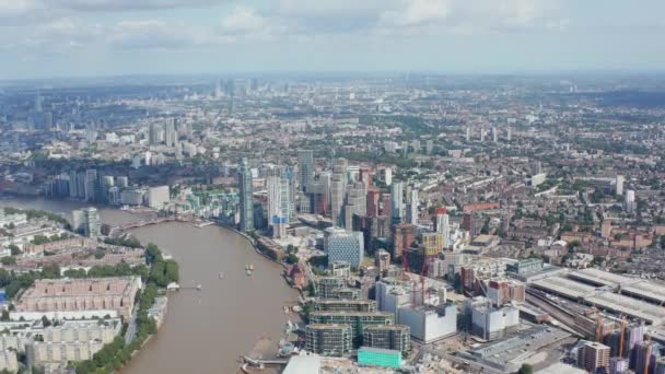 Backwards fly high above city. Modern residential building at bank of Thames river. Panoramic aerial view of large town. London, UK — Stock Video