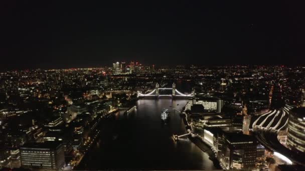 Обратно летим над Темзой. Вид с воздуха на подсвеченный Тауэрский мост белого цвета. Раскрытие осколков небоскреба. Лондон, Великобритания — стоковое видео