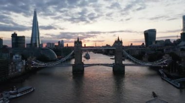 İleri, Thames Nehri üzerinden eski ve ünlü Tower Köprüsü 'ne doğru uçuyor. Üst geçitten alçak uçuş. Renkli günbatımı gökyüzü. Londra, İngiltere