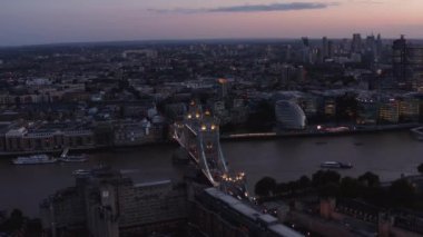 Tower Köprüsü 'ndeki Thames nehrinde yüzen teknelerin hava görüntüsü. Akşamları ünlü bir köprüyü aydınlattı. Londra, İngiltere