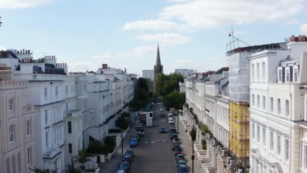 Dopředu proletět ulicí s bíle natřenými domy. Vysoká věž kostela v parku na konci ulice. Londýn, Velká Británie — Stock video