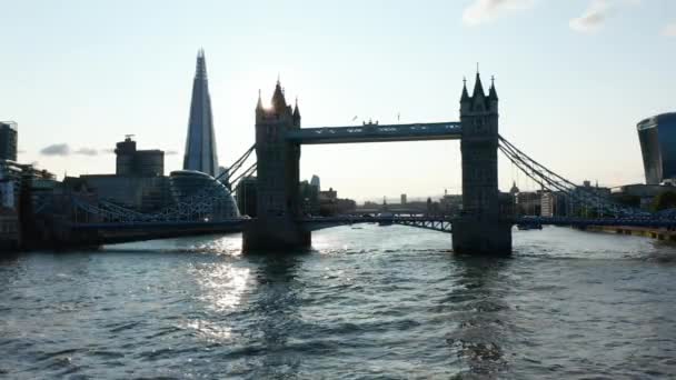 Vista de ángulo bajo del puente de la torre y el rascacielos Shard contra el sol. Bajo vuelo sobre la superficie del río Támesis. Londres, Reino Unido — Vídeos de Stock