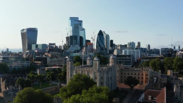 Voorwaarts vliegen boven middeleeuwse stenen kasteel en moderne hoge wolkenkrabbers op de achtergrond. Oude Witte Toren als onderdeel van Tower of London complex. Londen, Verenigd Koninkrijk — Stockvideo