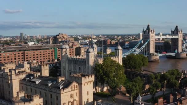 後方ロンドン中世の城の複合体のタワーを明らかにする。背景にある有名なタワーブリッジ。明るい午後の日差しに照らされた壁。イギリスのロンドン — ストック動画