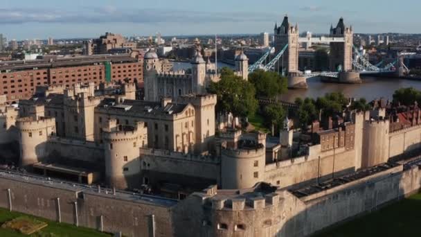 Przód leci nad Tower of London w złotej godzinie. Imponujące kamienne umocnienia średniowiecznego zamku. Stara Biała Wieża z czterema narożnymi wieżami i Union Jack na biegunie. Londyn, Wielka Brytania — Wideo stockowe