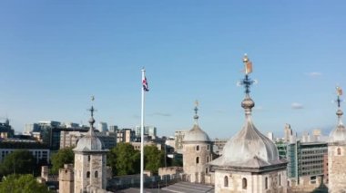 Londra Kulesi 'nin tepesindeki Panorama Virajı. Taş kalenin çatısındaki direkte bulunan dört kuleyi ve Union Jack 'i kapatın. Arka planda modern iş merkezi. Londra, İngiltere
