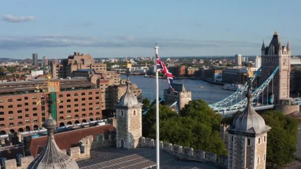 Union Jack hafifçe el sallıyor. Beyaz Kule 'nin ve Londra Kulesi' nin geri kalanının geçmişi ortaya çıktı. Arka planda Thames Nehri 'nin karşısındaki Kule Köprüsü. Londra, İngiltere — Stok video