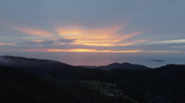 İbiza, Balear Adaları, İspanya 'daki siluetli dağların ve denizin üzerinde gün batımını gösteren hava görüntüleri..