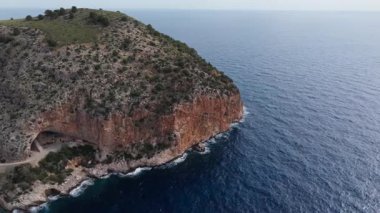 Dik bir uçurumun görkemli hava manzarası derin mavi Akdeniz 'e düşüyor. Promontory 'nin altındaki doğal mağara..