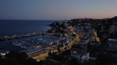 Mallorca, İspanya 'da yat dolu bir marinanın havadan görüntüsü. Alacakaranlık şehrin sokaklarını ve Akdeniz 'i aydınlatıyor..