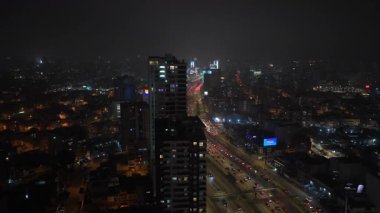Peru, Lima şehir merkezinin hava gece görüşü. Yüksek binalar ve yoğun araba trafiğiyle dolu bir otoyolu çevreleyen gökdelenler..