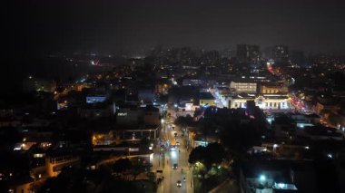 Lima, Peru 'nun aydınlık şehir manzarasının gece görüşü, caddeleri araç trafiği ve modern binalarla gösteriyor.