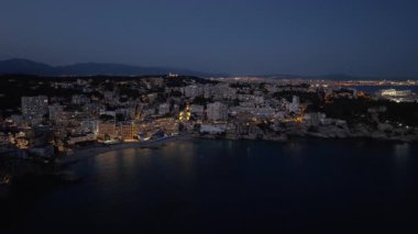 İspanya 'nın Mallorca kentindeki aydınlık bir şehrin görkemli hava manzarası, gece Palma kenti yakınlarındaki sakin Akdeniz kıyısında yer alıyordu..