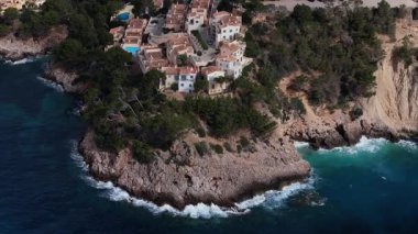 Mallorca kıyısındaki kayalık bir uçuruma kurulmuş yüzme havuzlu lüks villaları gösteren Idyllic hava perspektifi..
