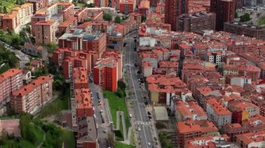 Bilbao 'daki bir yerleşim yerinin yüksek açılı görüntüsü terasotta çatısı ve caddelerde şehir trafiği olan apartman bloklarını gösteriyor..