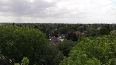 Yüksek açılı hava manzarası Hamburg, Almanya 'da bir banliyö mahallesine yavaşça iniyor, yemyeşil ağaçlar arasında kırmızı çatıları olan evleri ortaya çıkarıyor.