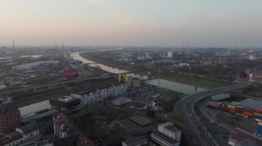 Mannheim, Almanya 'nın hava görüntüsü, sanayi bölgesinde uçuyor. Yoğun karayolu trafiği, gün batımında Neckar nehri üzerindeki bir köprüyü geçer..