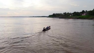 Amazon Nehri 'nin kıyısındaki yoğun ormanlarla çevrili uzak köyü gösteren geniş bir hava manzarası..
