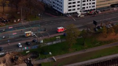 Kuzey Avrupa 'nın büyük bir şehrinde acil durum müdahalesi sırasında sokakta parlayan ışıkları olan bir ambulansın hava perspektifi.