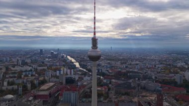 Alexanderplatz, Berlin, Almanya 'daki ikonik televizyon kulesinin muhteşem hava görüntüsü. Bulutlu gökyüzünün altında uzanan şehir manzarası.