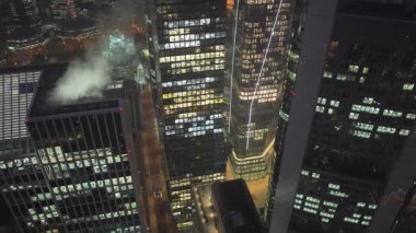 Omniturm da dahil olmak üzere Frankfurt 'un hareketli finans bölgesinin üç ayaklı hava görüntüsü. Aydınlatılmış gökdelenler ve modern kuleler geceleri şehir manzarasını tanımlar.