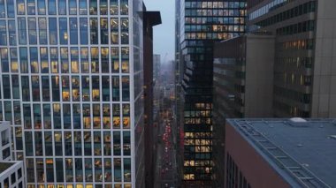 Şehir merkezindeki finans bölgesinin aydınlık pencerelerinde geç saatlere kadar çalışan insanların bulunduğu modern ofis binalarının hava manzarası..