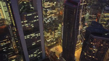 Gün batımından sonra Frankfurt bankacılık bölgesinin aydınlık gökdelenleri ve kuleleri üzerinde uçan hava manzarası. Modern şehir gece manzarası.