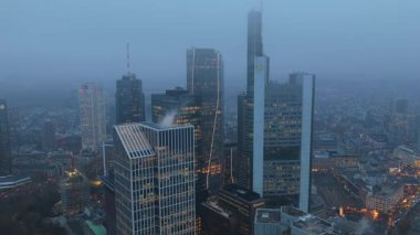 Frankfurt bankacılık bölgesinin hava manzarası Commerzbank Kulesi ve TaunusTurm gibi modern gökdelenler alacakaranlıkta yoğun sisten ortaya çıkıyor..