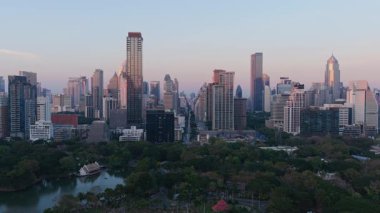 Günbatımında modern gökdelenler ve Lumphini Park ile Bangkok 'un benzersiz üç ayaklı hava manzarası. Tayland 'da şehir merkezi manzarası.