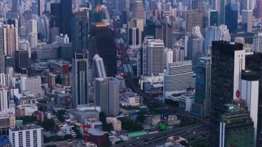 Bangkoks 'un hareketli şehir manzarasının havadan görüntüsü. Alacakaranlık saatinde gökdelenler otoyolların ve gökdelen raylarının üzerinde..