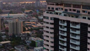 Günbatımında Chao Phraya nehri ve Bangkok siluetini gözler önüne seren, modern bir yerleşim yerinden uzaklaşan hava manzarası..