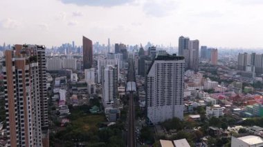 Yüksek demiryolu boyunca ilerleyen bir BTS Skytrain ile Bangkok şehir manzarası. Konut gökdelenleri olan modern metropol alanı.