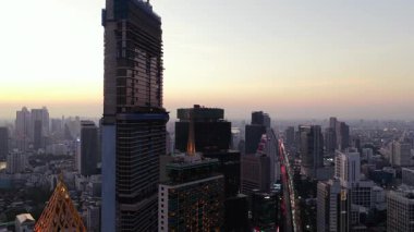 Gün batımında Bangkoks 'un finans bölgesinin havadan görüntüsü. Modern gökdelenlere ve caddelerde yoğun trafiğe sahip.