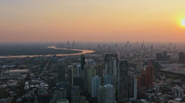 Turuncu günbatımında modern gökdelenler ve Chao Phraya nehri ile Bangkok 'un gökyüzü manzarası. Puslu Asya şehir manzarası.